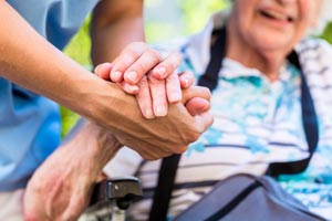 A carer holding an elderly womans hand