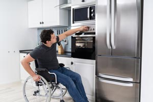 A man in a wheelchair using an oven
